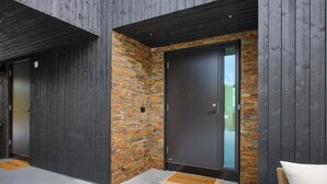 Un bâtiment moderne doté de deux portes en bois foncé et d’un mur en pierre.