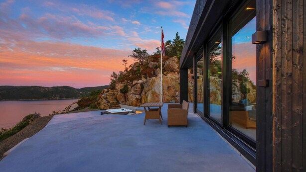 Une terrasse extérieure moderne dotée d’un jacuzzi, de sièges et d’un mât pour drapeau.
