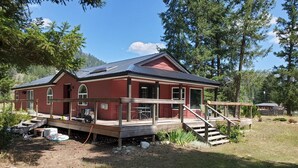 Uma casa vermelha com varanda, deck e escadaria que leva à entrada.