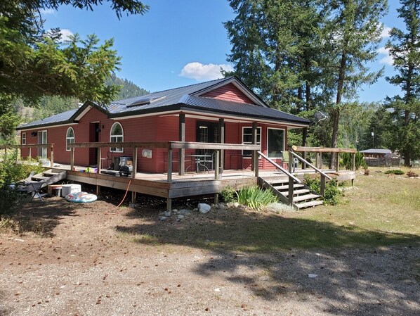 A red house with a porch, a deck, and a staircase leading to the entrance. - Old Cowboy Ranch Guesthouse - CALL FOR AVAILABILITY (Westbridge)