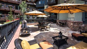 Une terrasse extérieure dotée de meubles en osier, d’un sol en pierre et de grands parasols.