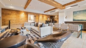 Un salon moderne doté d’une cheminée, de fauteuils en cuir et d’un coin repas avec des tables en verre.