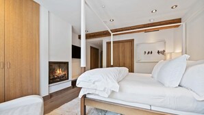 Une chambre à coucher moderne avec un lit, une cheminée, une armoire en bois et un tableau au mur.