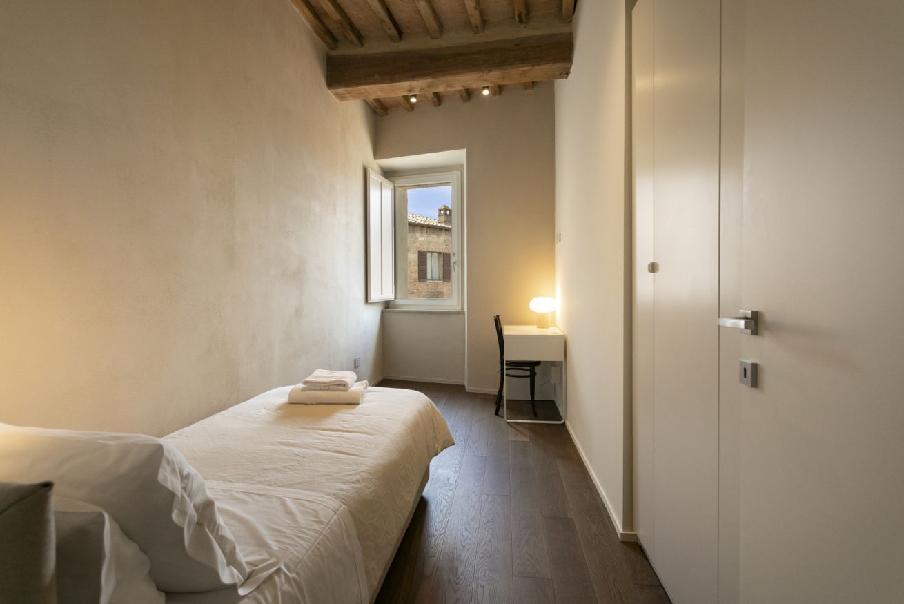 A bedroom with a bed, a desk, and a chair.