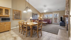 A dining area with a wooden table and chairs, a kitchen with a microwave, and a living room with a couch and a TV. - Two in One! Full Condo with Lock-off Connecting Suite (Reeds Spring)