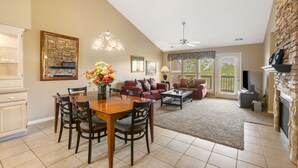 A spacious living room with a dining area, a fireplace, and a stone accent wall. - Cozy & Charming Condo at StoneBridge Village Resort (Reeds Spring)