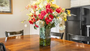 A dining table with a vase of flowers in the center. - Cozy & Charming Condo at StoneBridge Village Resort (Reeds Spring)