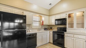 A kitchen with white cabinets, a black refrigerator, a microwave, a stove, and a dishwasher. - Golf Condo for Two at Beautiful StoneBridge Village Resort (Reeds Spring)