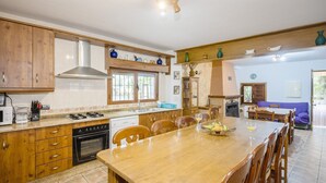 Une cuisine spacieuse avec des meubles en bois, un grand îlot central et un coin repas agrémenté d’un canapé bleu.