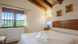 Une chambre d’hôtel avec un grand lit, une tête de lit en bois, une table de chevet avec une lampe et une fenêtre avec des rideaux.