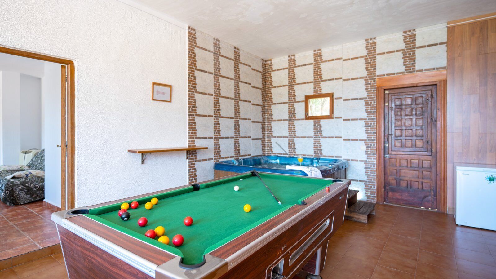 A pool table with balls, a hot tub, and a wooden door.