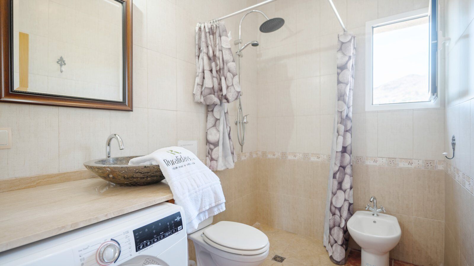 A bathroom with a wooden vanity, a sink, a toilet, and a shower area.
