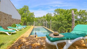 Un espace piscine avec des chaises longues et un mur en pierre.