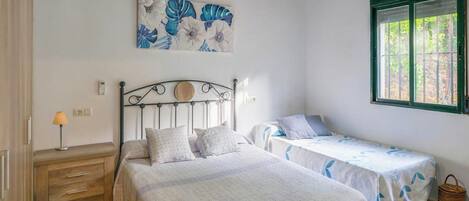 Ein Schlafzimmer mit einem Bett, zwei Nachttischen, einer Lampe, einem Fenster und einem Bild an der Wand.