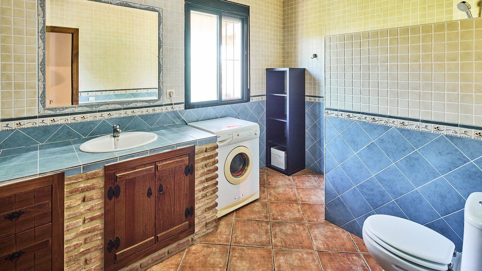 A bathroom with a sink, washing machine, and toilet.