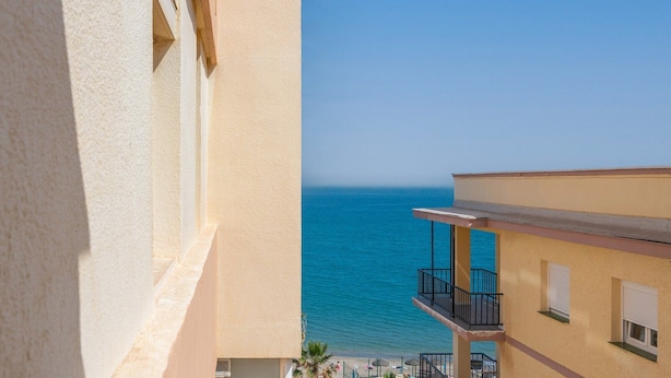 A building with a balcony overlooking a clear blue sea. - Lux Playa Fuengirola by Ruralidays (Málaga)