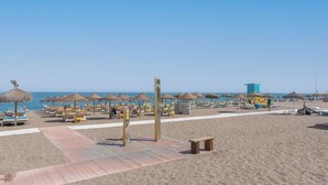 A beach with sun loungers, umbrellas, and a lifeguard tower. - Lux Playa Fuengirola by Ruralidays (Málaga)