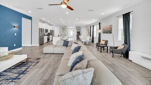 A spacious living area with a large sectional sofa, a dining table, and a kitchen in the background. - Modern Family Villa With Private Pool and Hot Tub (Reunion)
