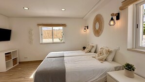 A bedroom with two beds, a TV, a window with a view, and wall-mounted lights. - Vila Luisa Anabela 6/8 Personnes Piscine et Jacuzzi (Albufeira)