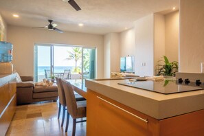 A modern kitchen with a large island, a dining area with a view of the ocean, and a ceiling fan. - Costa brava  (Puerto Aventuras)