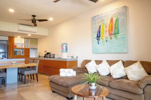 A modern living room with a sofa, a coffee table, and a painting of sailboats on the wall.