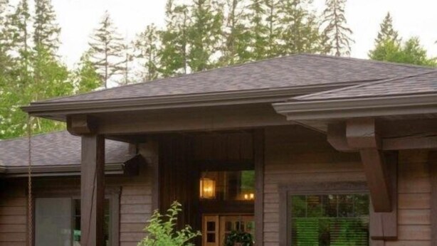 A two-story house with a covered porch, a front door with a wreath, and a bench outside.