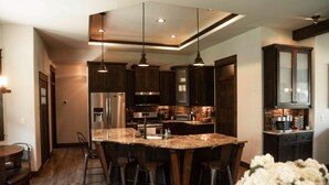 A modern kitchen with dark wood cabinets, stainless steel appliances, and a central island with bar stools.