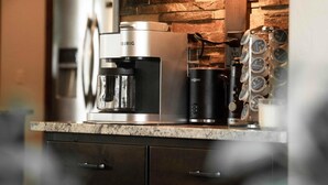 A kitchen with dark cabinets, a coffee maker, and a coffee grinder.