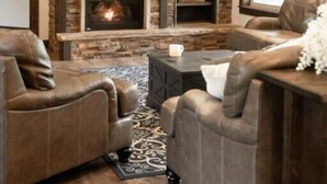 A living room with a stone fireplace, leather sofas, and a mounted deer head.