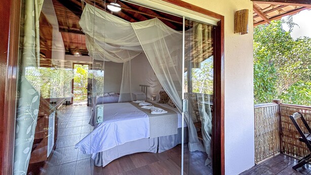 Une chambre avec une porte en verre, un lit et une vue sur la verdure.