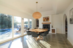 A modern dining area with a round table, black chairs, and a large window. - Design newly remodeled  villa. 10 minutes from Palm Springs (Desert Hot Springs)