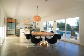Une cuisine moderne avec un coin repas, de grandes fenêtres et une vue sur une piscine.