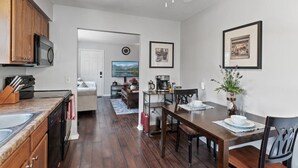 Une cuisine moderne avec un plancher en bois foncé, un coin repas avec une table et des chaises en bois, et un ventilateur de plafond.