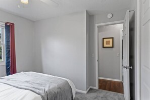A bedroom with a bed, a door, and a wall-mounted picture.