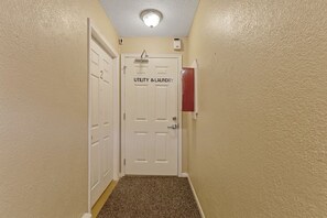 A hallway with a door labeled 'UTILITY & LAUNDRY,' carpeted floor, and a light fixture on the ceiling.