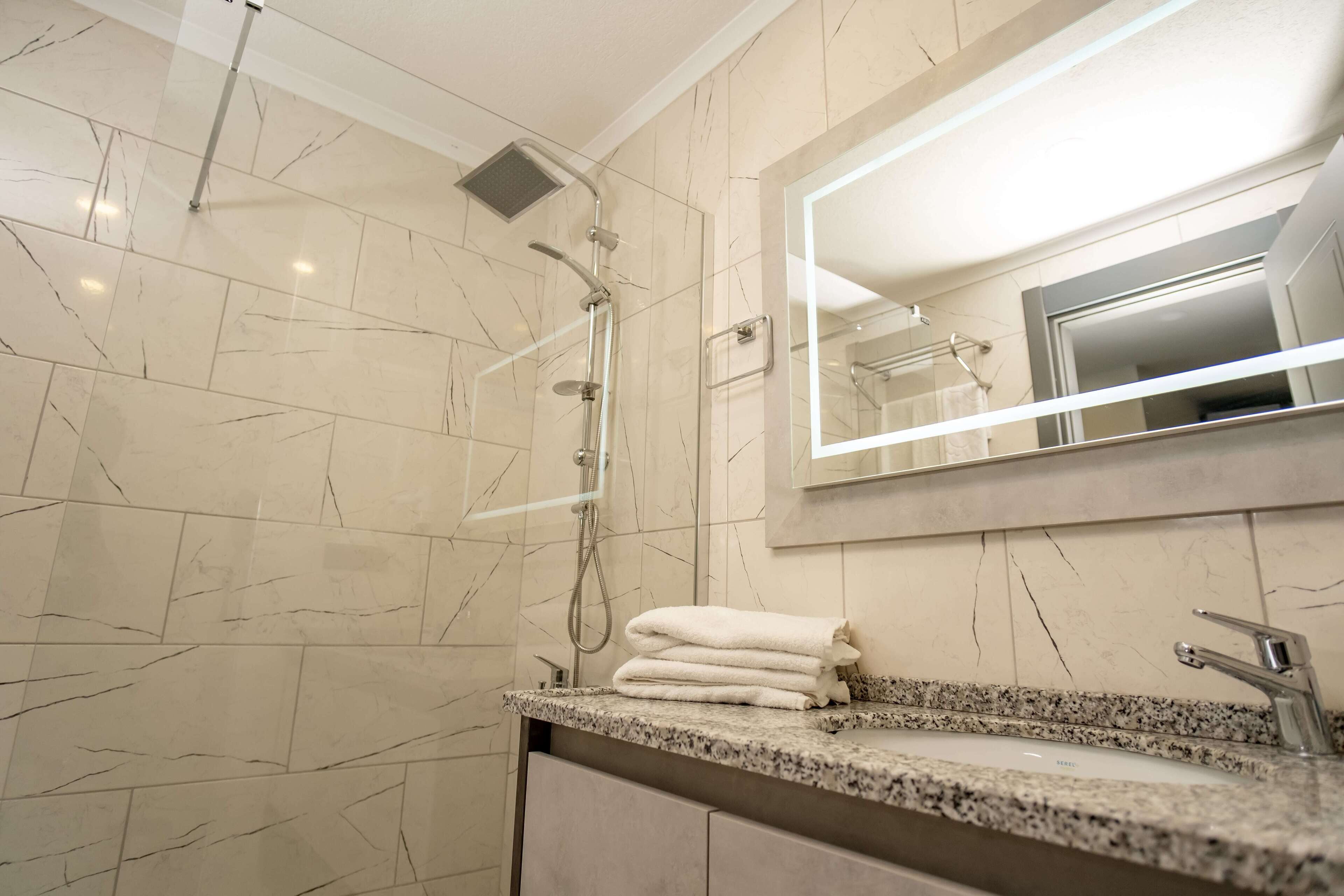 A modern bathroom with a shower, a sink with a mirror, and a towel rack.