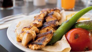 A plate of grilled chicken skewers with vegetables on a table.