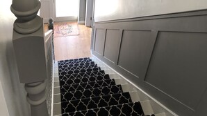 A staircase with a patterned carpet, a decorative wall with a mirror, and a welcome mat. - Cleomack House
Home from Home @Mourne Mountains  (Hilltown)