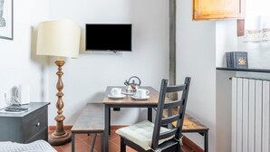 Une pièce avec une table en bois, deux chaises, une lampe, un téléviseur et un radiateur.