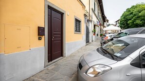 Une rue étroite avec un immeuble jaune, une porte marron et des voitures garées.