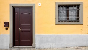 Une porte marron avec une petite fenêtre au-dessus, une boîte aux lettres et un panneau portant le chiffre « 7 » sur le mur.