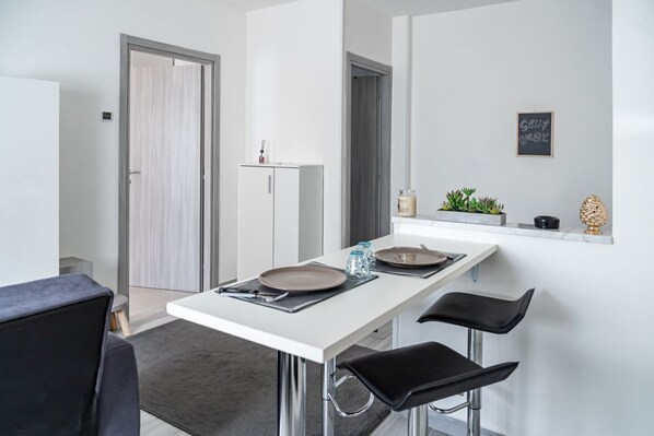 A modern kitchen with a white countertop, two black bar stools, a white cabinet, and a door with a frosted glass panel.