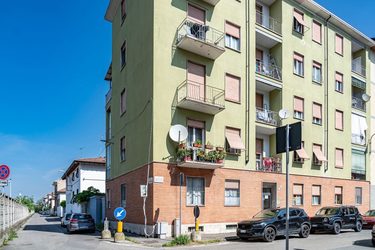 Un immeuble résidentiel à plusieurs étages, doté de balcons, d’antennes paraboliques et de voitures garées.