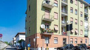 Un immeuble résidentiel à plusieurs étages, doté de balcons, d’antennes paraboliques et de voitures garées.