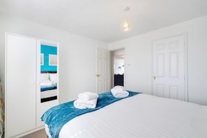 A hotel room with a bed, a wardrobe, and a door leading to another room.
