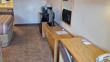 A hotel room with a bed, a desk with a telephone, a computer, and a mirror.