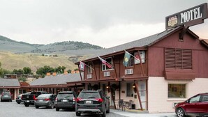 Ein Motel mit Schild, mehreren parkenden Autos vor der Fassade und einem Berg im Hintergrund.