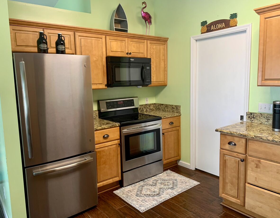 Una cocina compacta con gabinetes de madera, un refrigerador de acero inoxidable, un microondas y un horno.