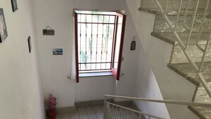 A staircase with a metal railing, a window with a red frame, and a potted plant.