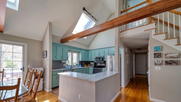 Une cuisine spacieuse avec des meubles de couleur turquoise, un grand îlot central et un escalier en bois.